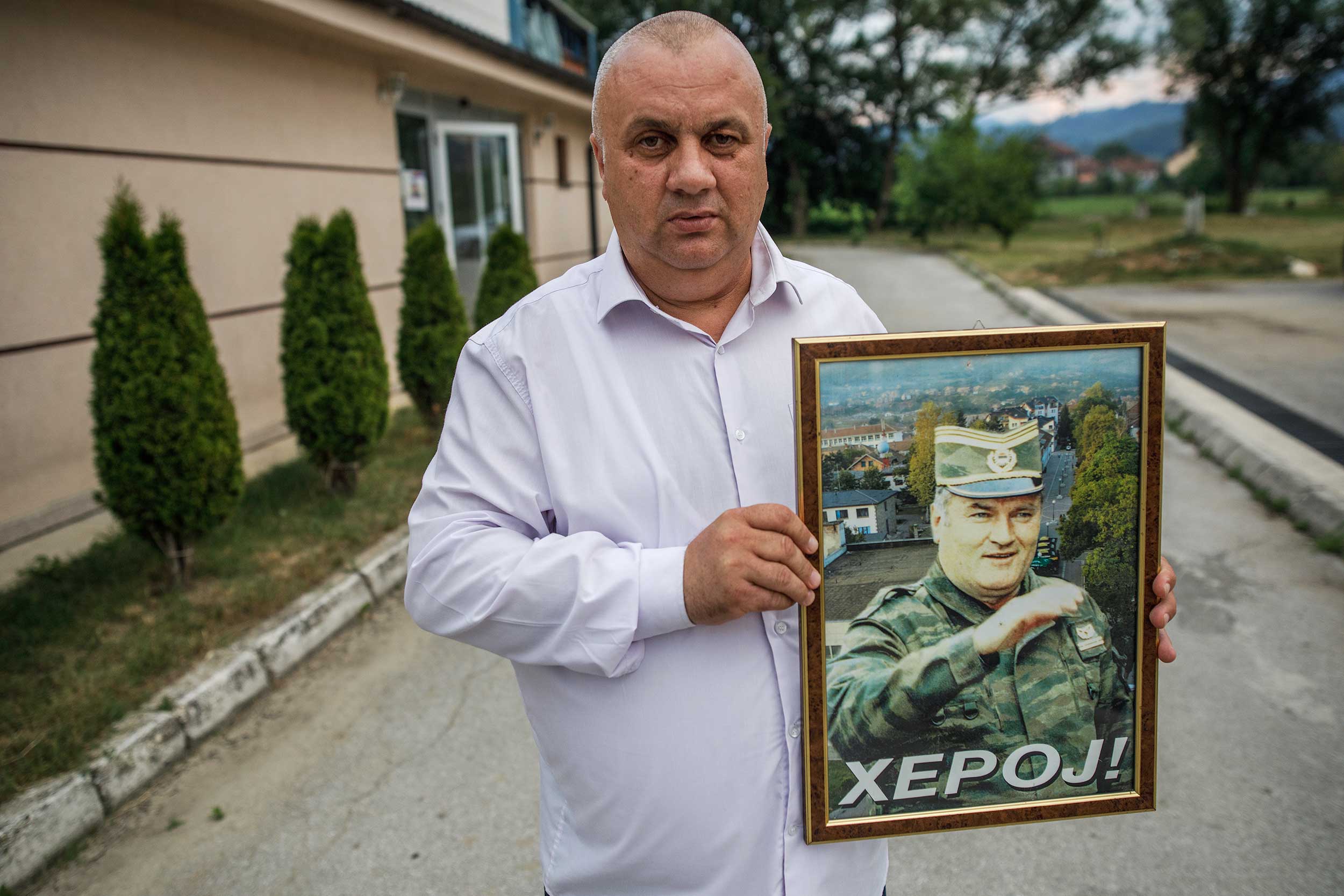 Vojin Pavlovic, an organiser of the "Srebrenica liberation day" event poses with a photo of Bosnian Serb war time military leader and convicted war criminal Ratko Mladic with a word "hero" written on it on July 11, 2020 in Bratunac, near Srebrenica, Bosnia and Herzegovina. As the 25th anniversary of Srebrenica genocide, in which over 8,000 Bosnian Muslim men and boys were killed by Serb forces is marked. © Damir Sagolj/Getty Images