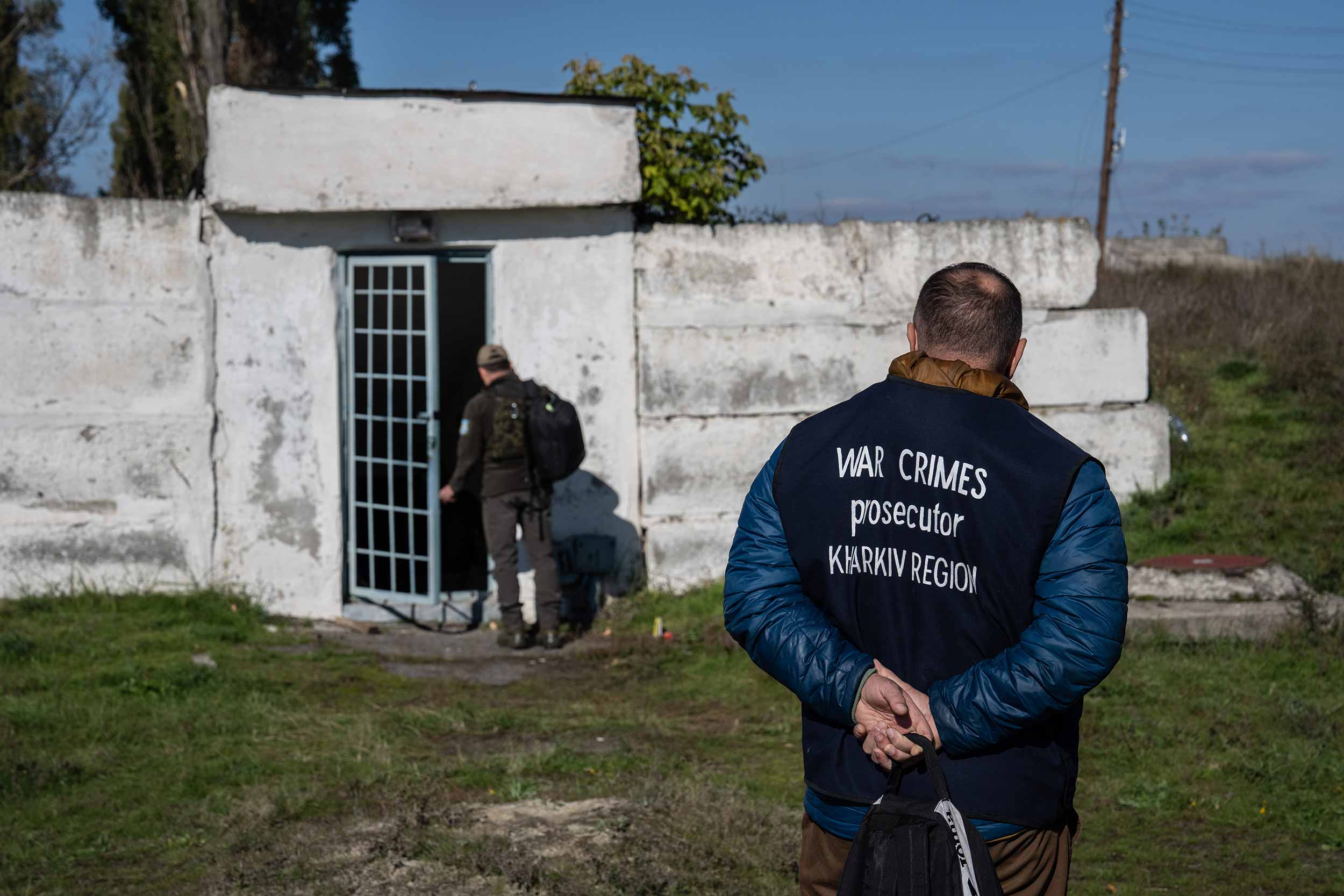 A war crimes prosecutor looks on as a police officer enters an underground air raid shelter that was believed to be used as a prison by Russian occupying forces during a search for evidence of war crimes on October 15, 2022 in Kupiansk, Kharkiv oblast, Ukraine. © Carl Court/Getty Images