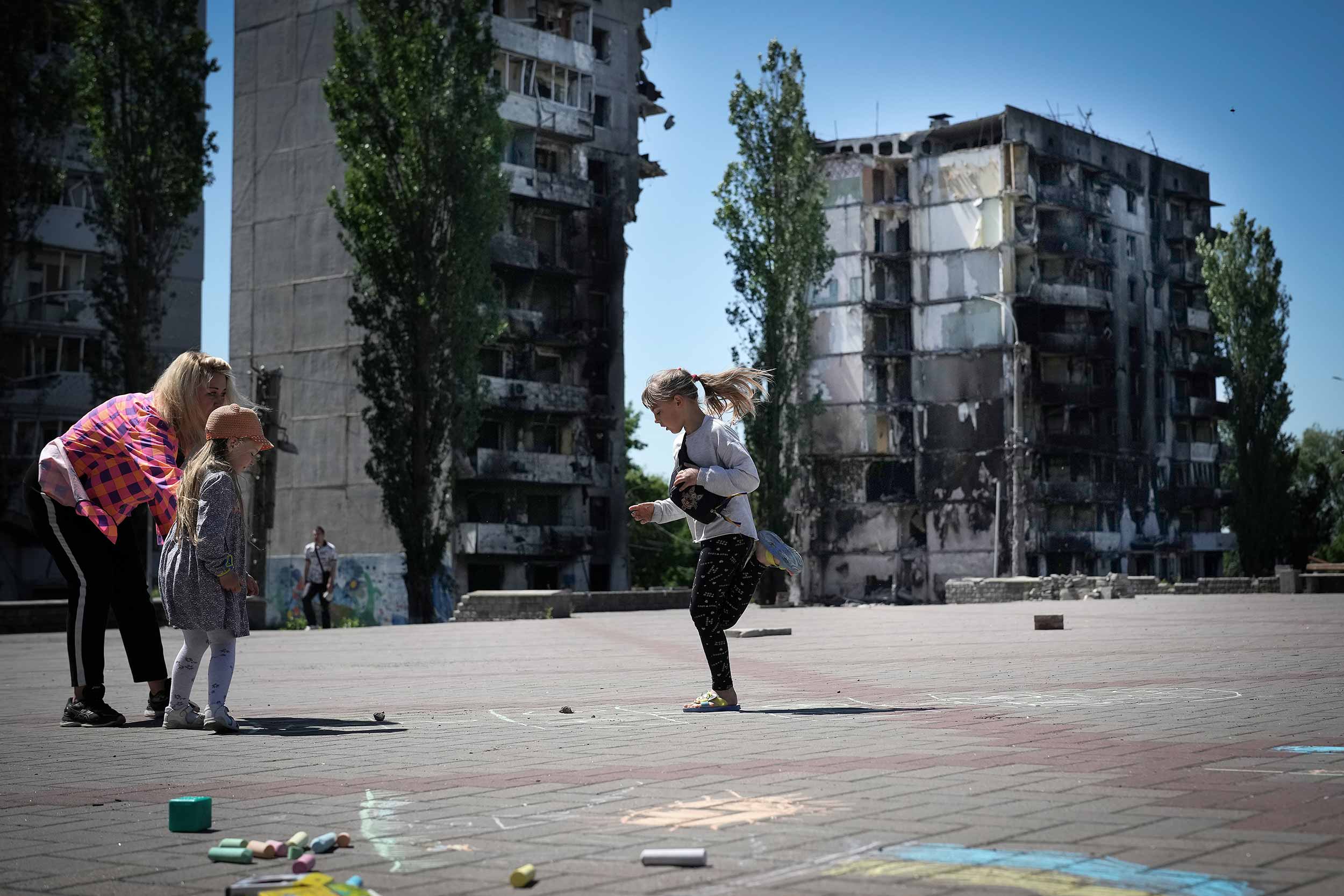 Volunteers from Borodianka community organise games and crafts for the children of the Kyiv suburb in the main square against the backdrop of a destroyed apartment blocks on June 03, 2022 in Borodianka, Ukraine. The small town was occupied and heavily damaged during the Russian invasion with many of the facilities for children destroyed. © Christopher Furlong/Getty Images